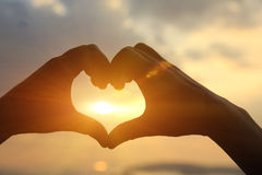 heart-shape-making-hands-against-bright-sea-sunset-sunny-golden-way-water-49407500